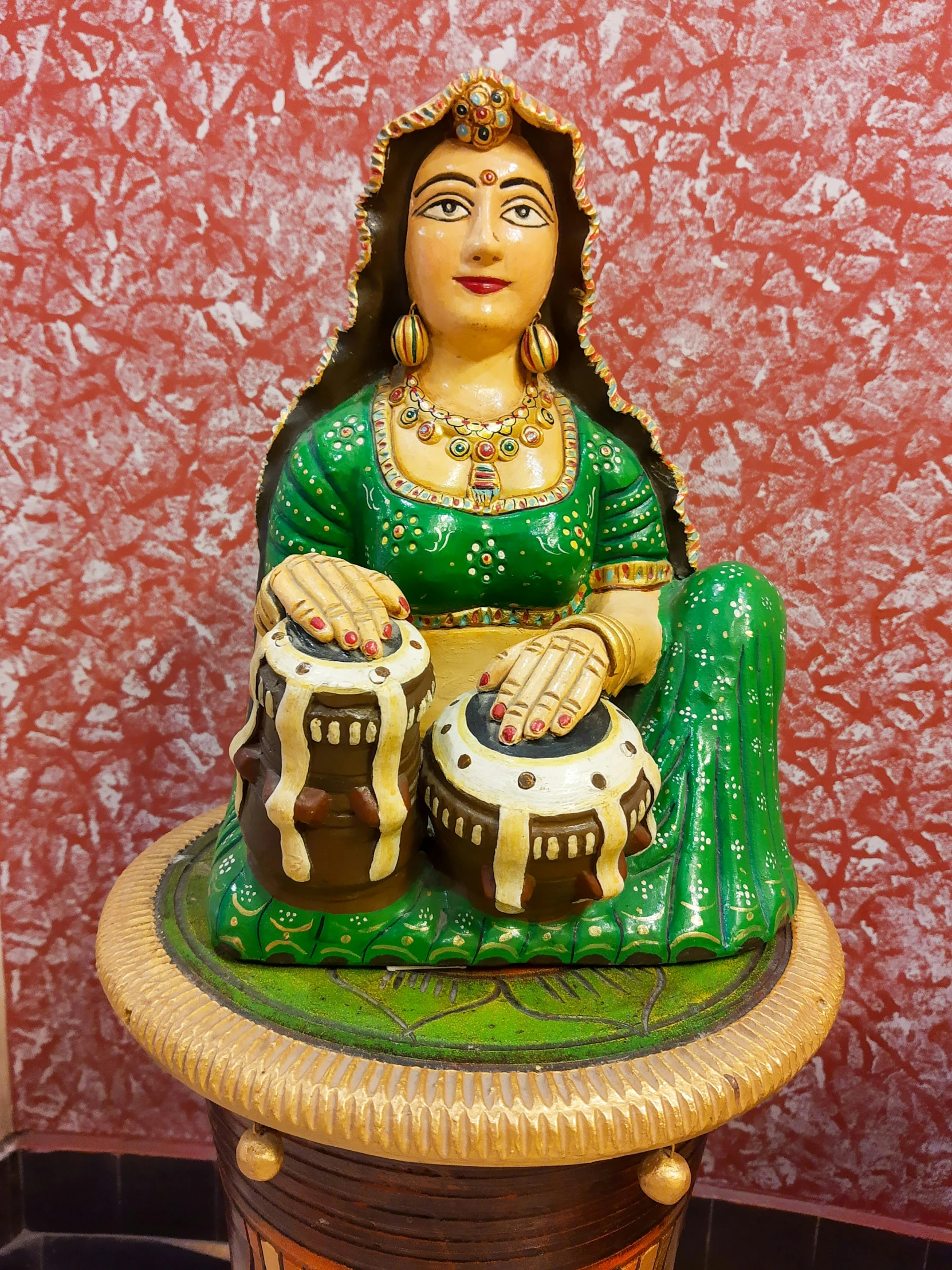 an ornate ceramic sitting female indian figurine holding two drums