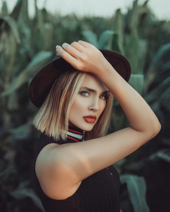 a blond woman in black shirt and hat looking at the camera