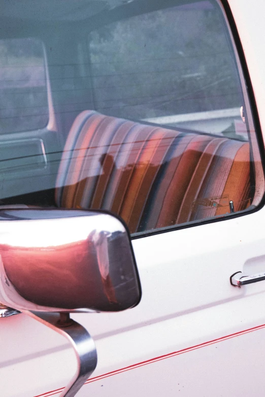 a window on a white van showing a row of striped pillows