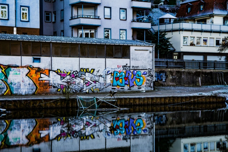 some graffiti that is on a wall next to water