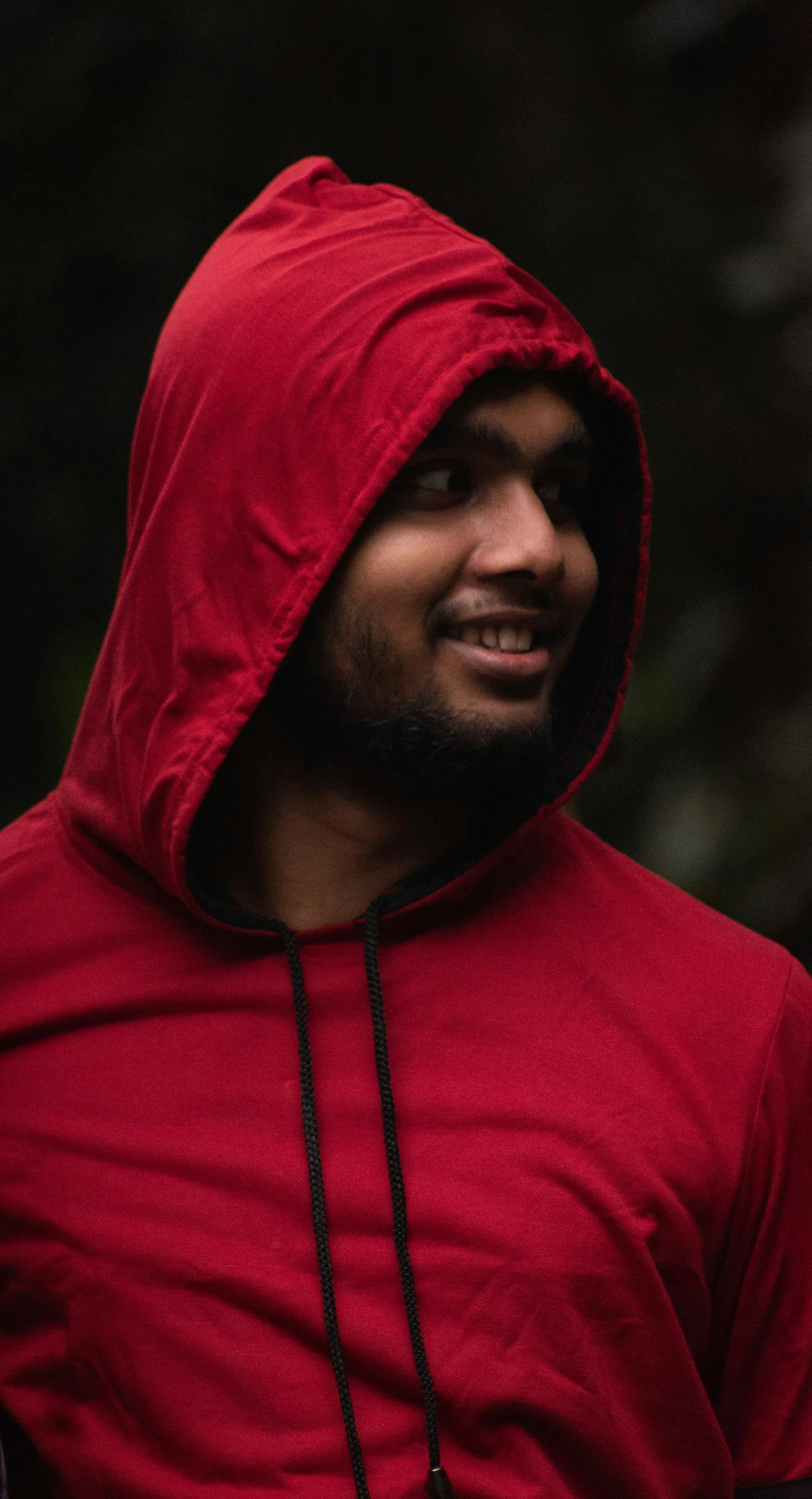 man in red hoodie standing outdoors in the rain