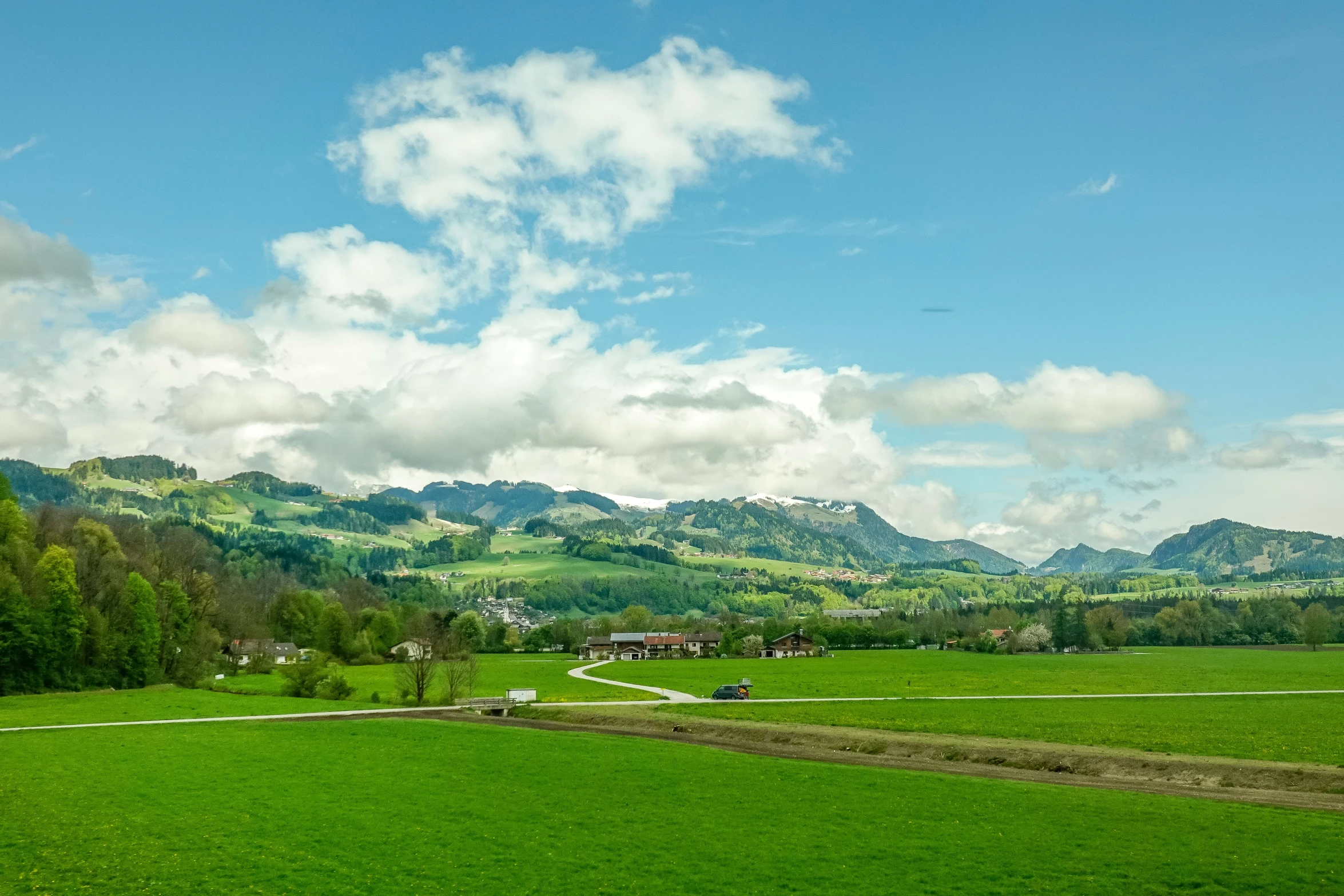 a lush green landscape with trees, hills and houses