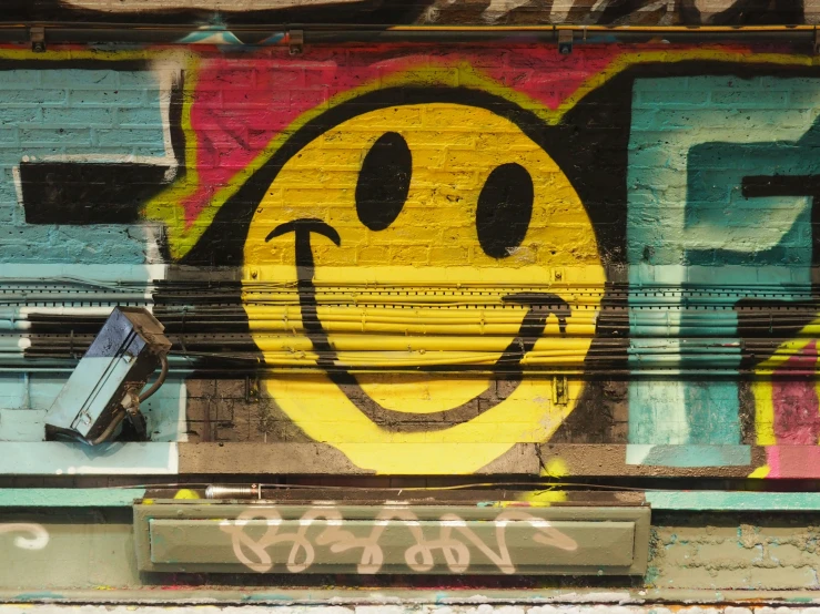 graffiti written on the side of a building with yellow smiling face painted on it