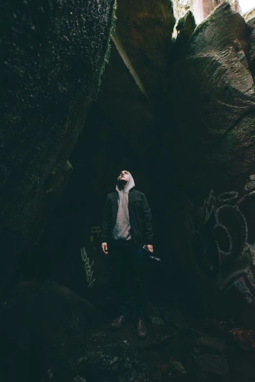 man standing with a rifle inside the middle of a cave