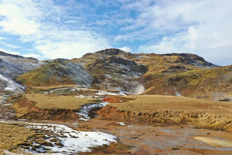 snow covers a mountain range as a small river cuts through the ground