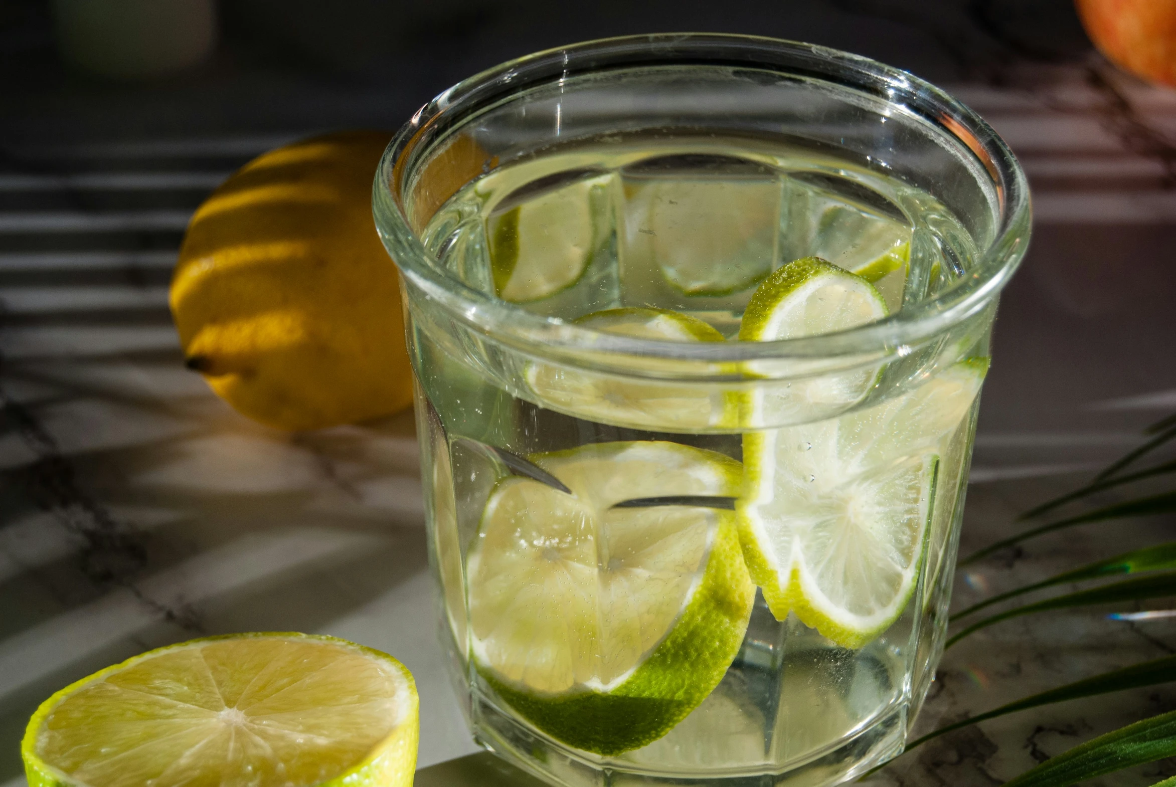 there is a glass of water with sliced limes