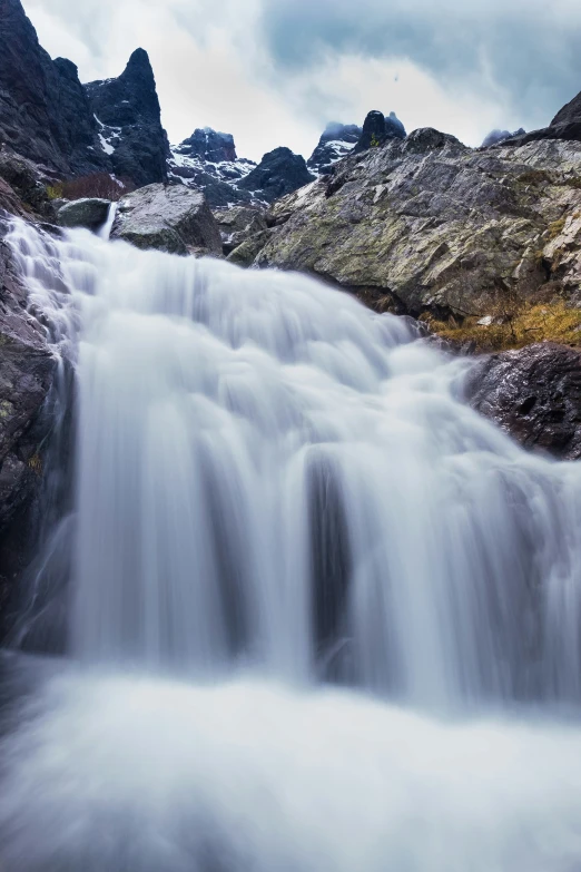 a waterfall cascade with mountain peaks in the background