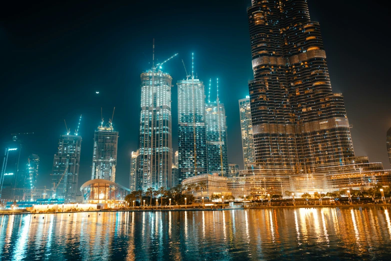 some tall buildings at night reflected in the water