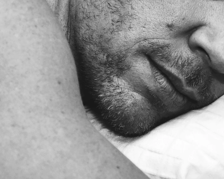 a closeup of a man sleeping with his head on his pillow