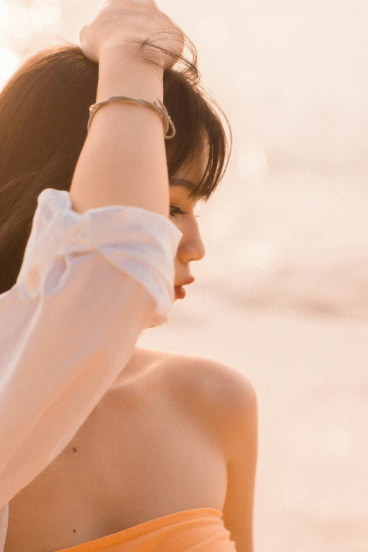 woman looking up with hand on head on beach