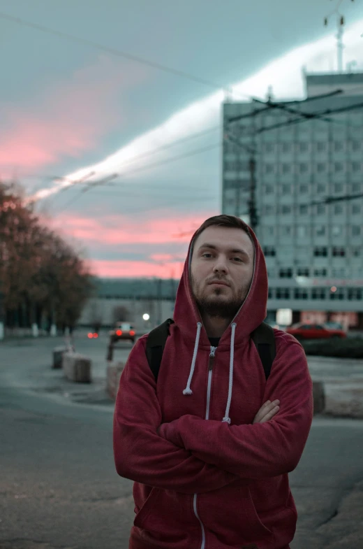 a man wearing a red hooded jacket standing on the street