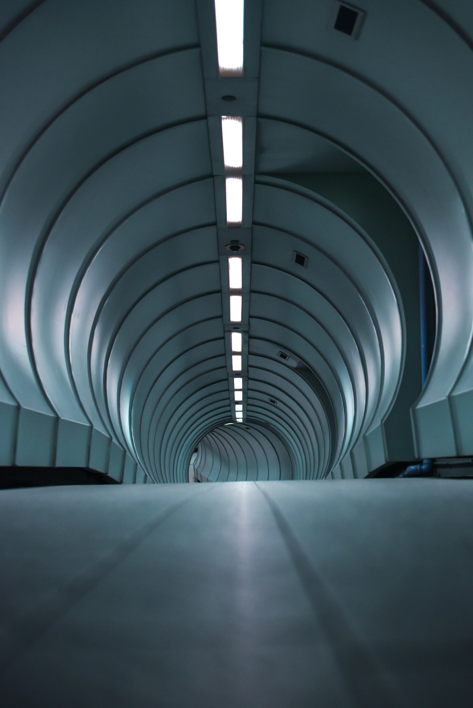 an underground walkway covered in a tunnel filled with light