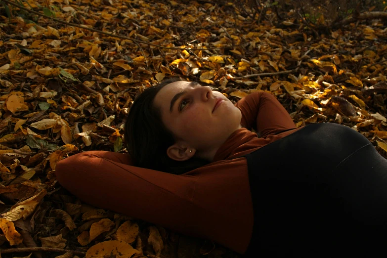 a woman is laying on the ground with some leaves