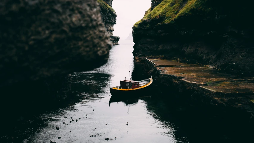 a yellow boat floats through an narrow channel