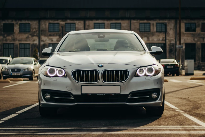 a white bmw car parked in front of some older cars