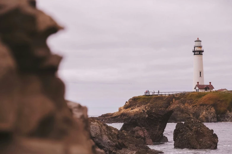 a white lighthouse on the coast near some rocks