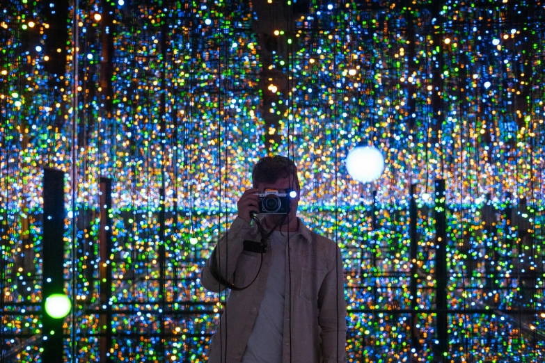 a person is taking a po of a sculpture that has brightly colored lights on it