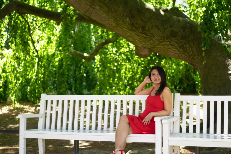 a beautiful woman sitting on top of a white bench