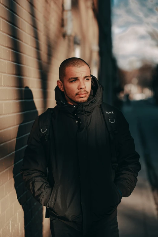 a man standing next to a building and leaning on a brick wall