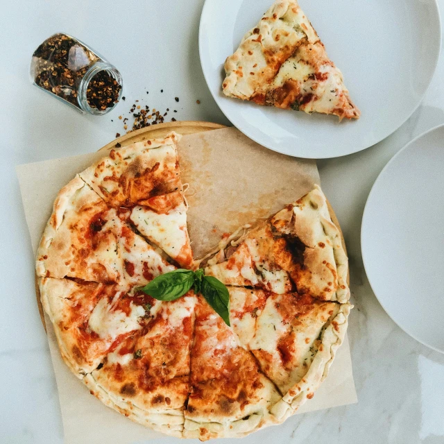 a pizza and slices of it are on plates