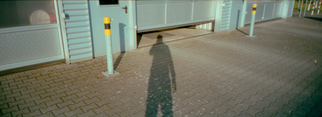 a shadow in the sidewalk next to a building