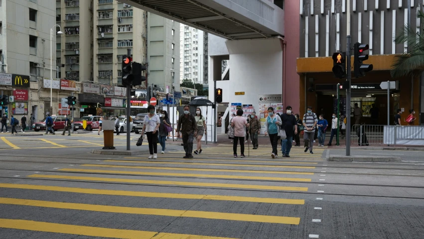 people walking down a street with yellow traffic lights