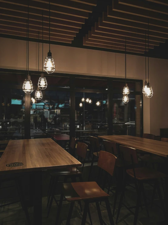 a restaurant filled with tables and hanging lights