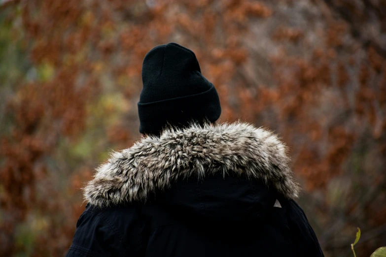 someone in a jacket looking at trees outside