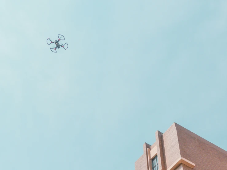 a tiny plane flying above a building on a clear day