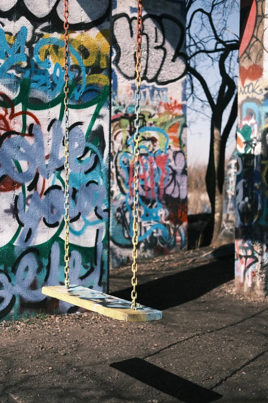 a piece of furniture suspended on chains near graffiti