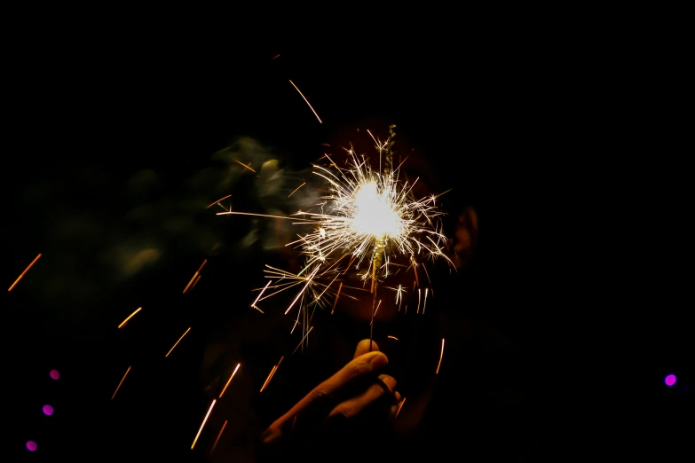 some people holding up sparklers with the light on