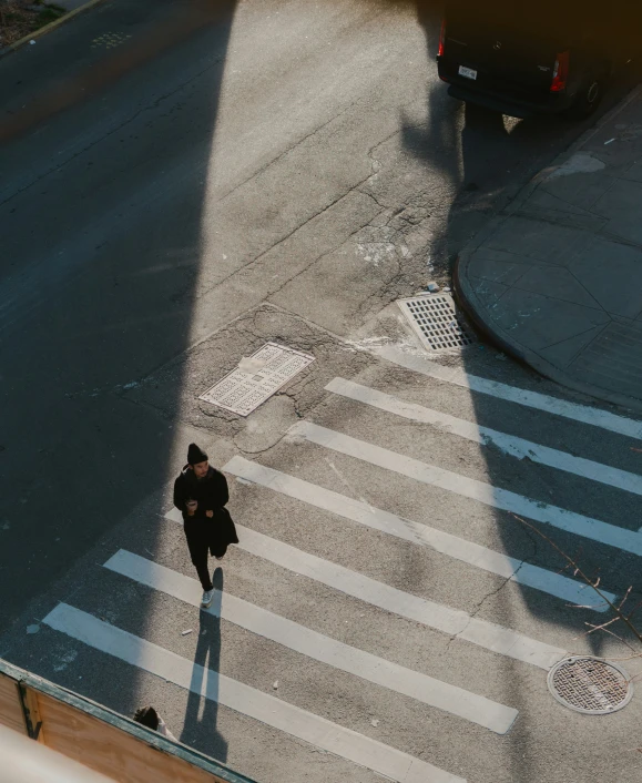 a pedestrian crosses an empty street in front of traffic lights