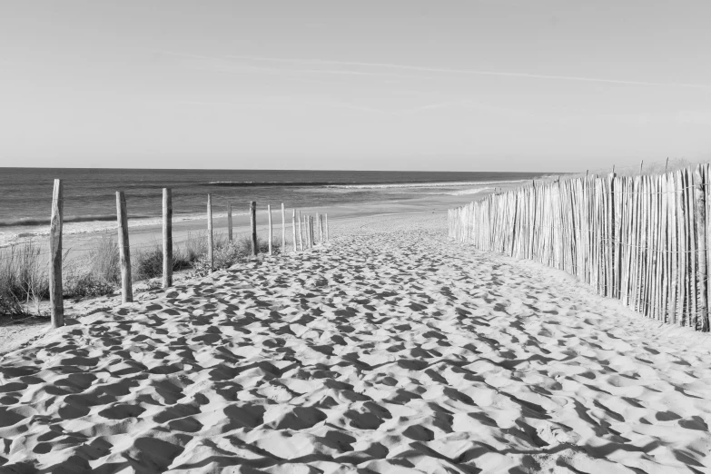 the beach has white sand and the fence is made of wire