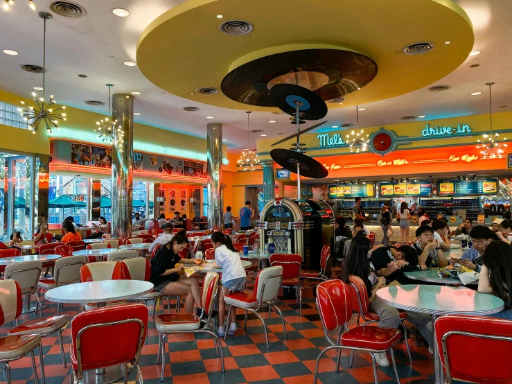 a dining area in an outdoor cafe with round and oval tables and checkered flooring