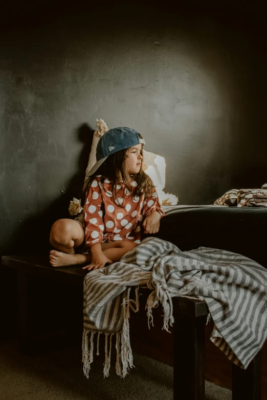 a girl sitting on a bed next to a teddy bear