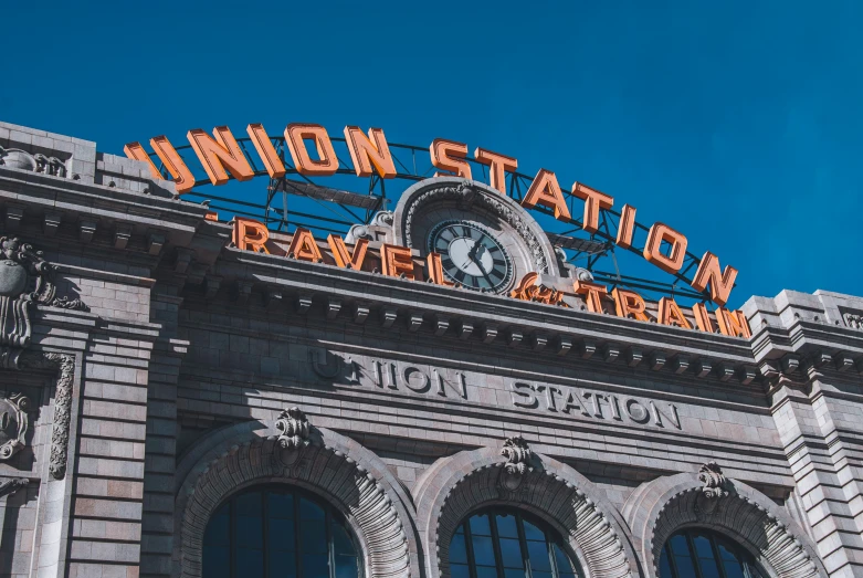 an old brick station building with neon sign above it