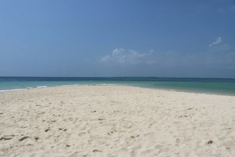 a sandy beach in front of a bright blue sky