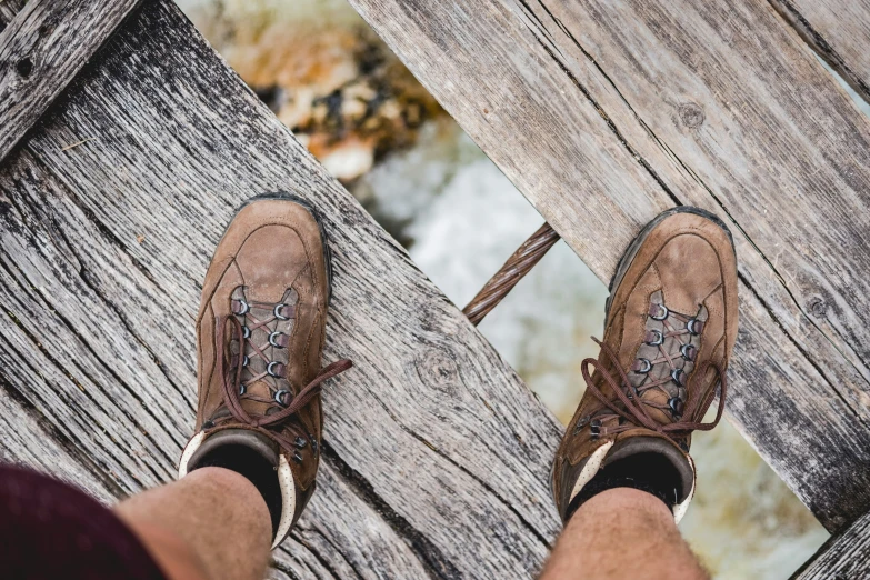 someone's feet standing on the side of a wood structure