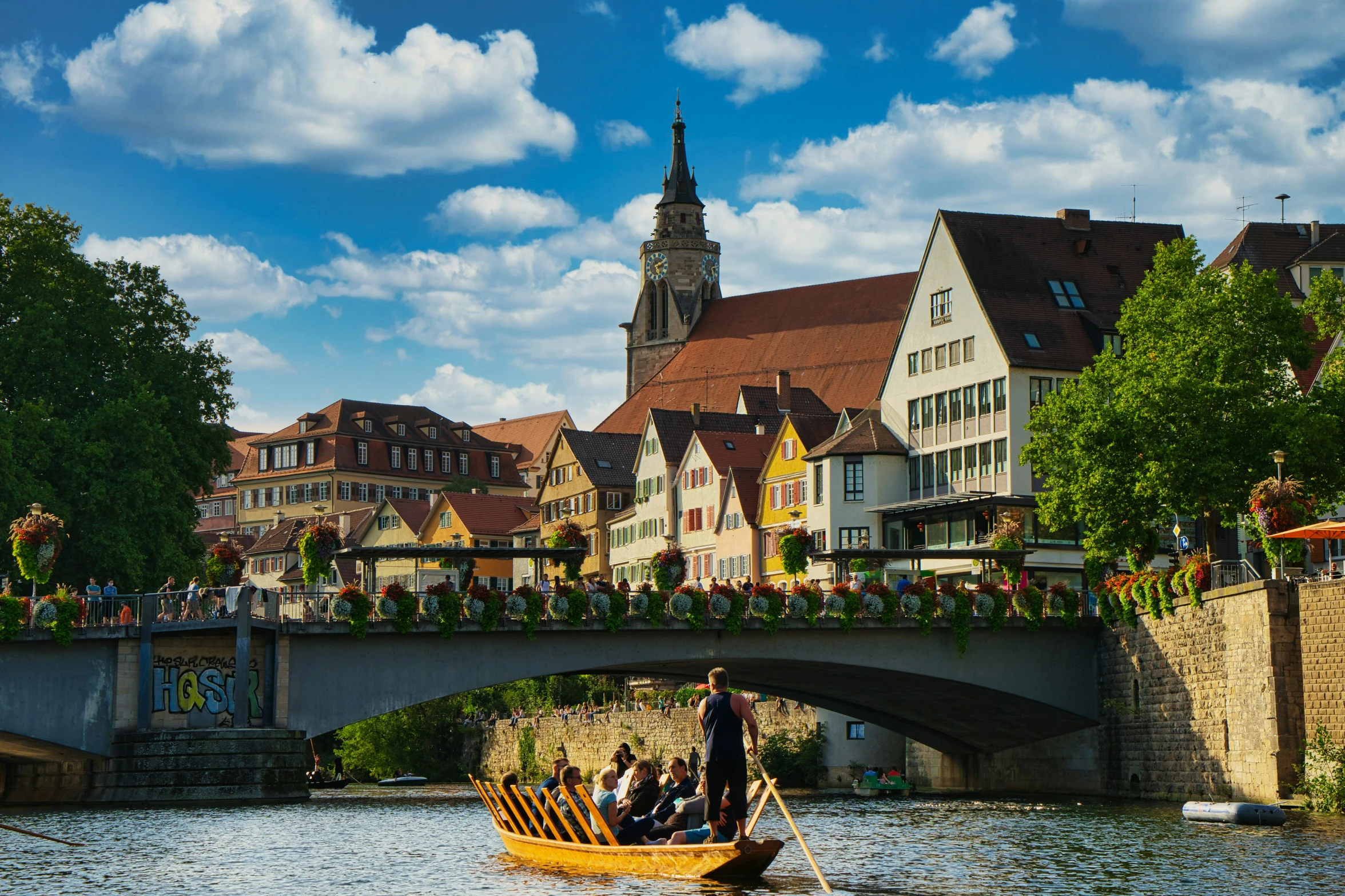 people ride a small boat under a bridge