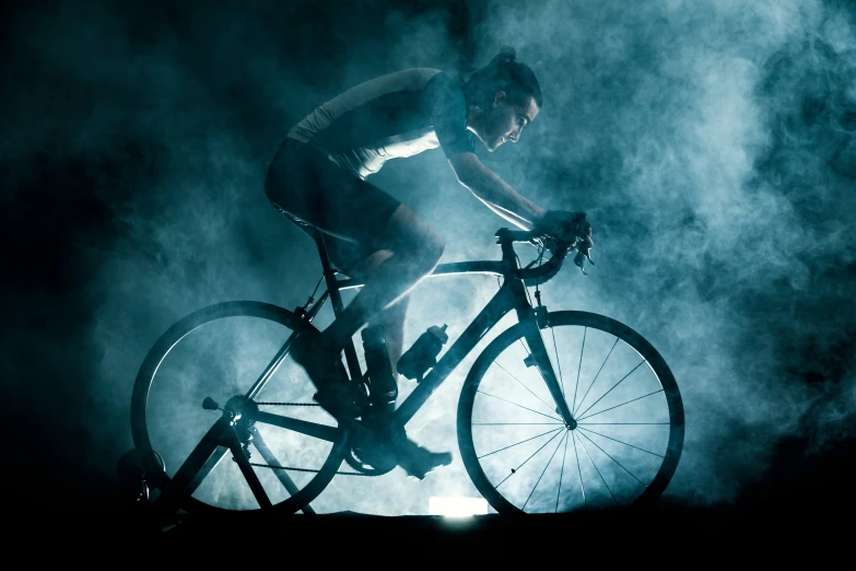 a cyclist is seen riding through smoke in the dark