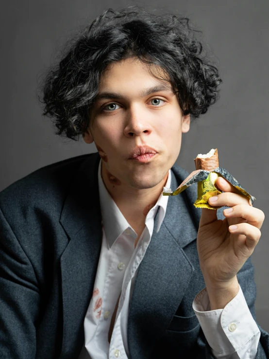 a man in a suit is holding a piece of broccoli