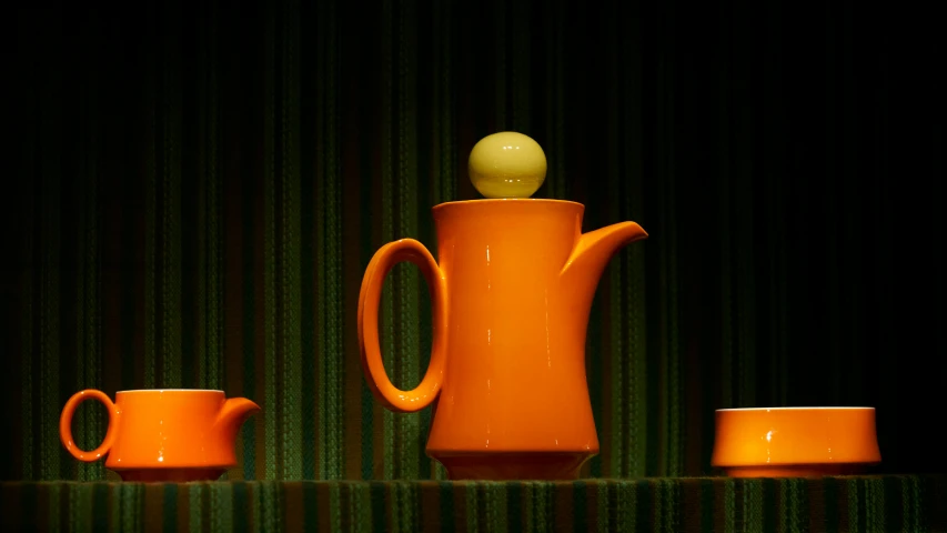 a ceramic set consisting of an orange mug and matching saucers