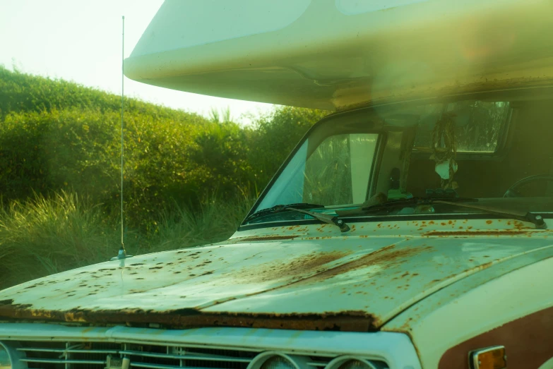 an old rusted car is parked in front of some bushes