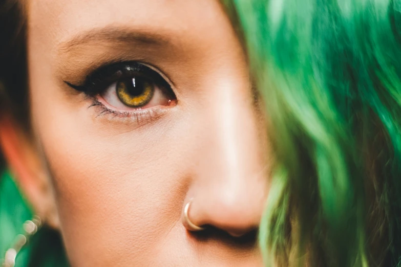 a woman with green hair and gold hoops