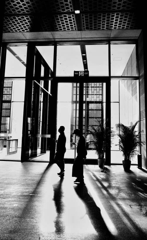 two people walking in a building with the doors open