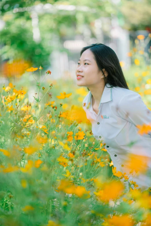 an asian woman standing in a field with yellow flowers