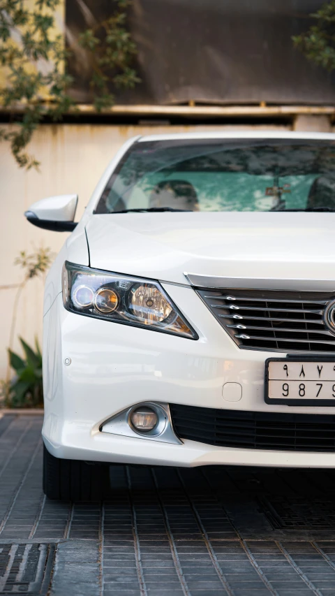 the front end of a white vehicle with a license plate