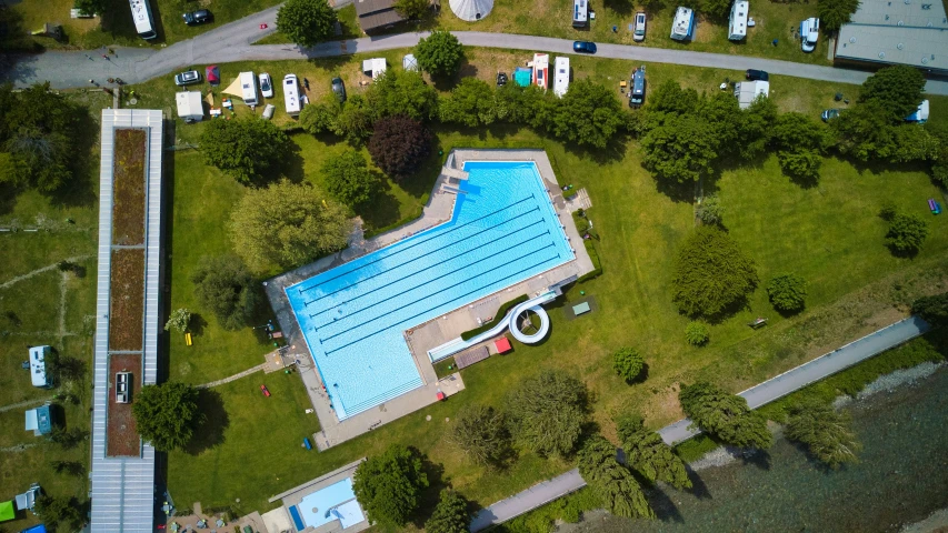 an aerial view of a swimming pool, with lots of green space
