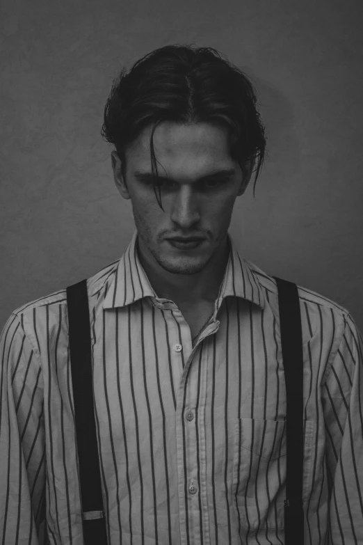 a man with suspenders looking down at the camera