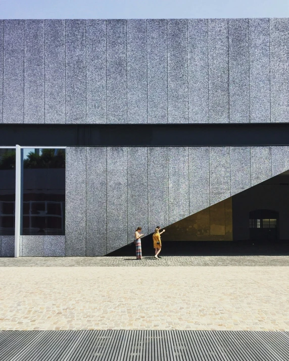 two boys in front of a gray building with a geometricly shaped entrance